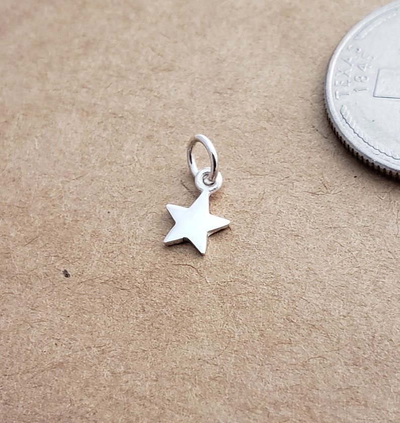 May include: A small silver star charm with a loop for attaching to a necklace or bracelet.