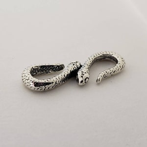 Puede incluir: Un cierre de serpiente de plata para la elaboraci&oacute;n de joyas. El cierre est&aacute; detallado con un patr&oacute;n de piel de serpiente texturizado.