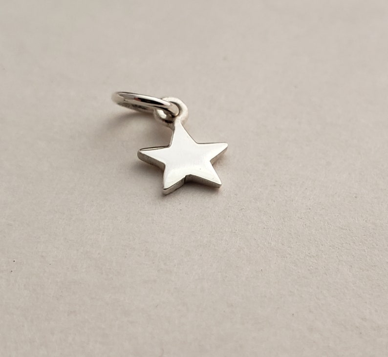 May include: A silver star charm with a loop for attaching to a necklace or bracelet.
