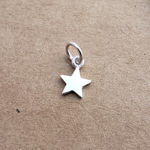 May include: A silver star charm with a loop for attaching to a necklace or bracelet.