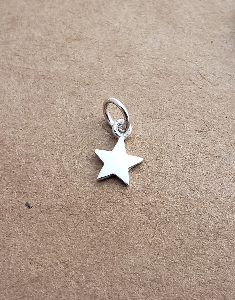 May include: A silver star charm with a loop for attaching to a necklace or bracelet.