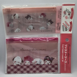 May include: Two pink Sanrio character fastener cases. The top case features multiple character illustrations. The bottom case has four characters on a checkered background. The packaging includes text in Japanese and English.