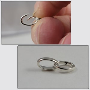 May include: Silver-toned metal clasp with a loop on one end and a hook on the other. The clasp is open and ready to be attached to a chain or other jewelry.