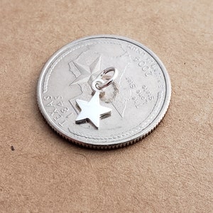 May include: A silver charm in the shape of a five-pointed star, shown next to a US quarter with the year 2004 and the state of Texas.