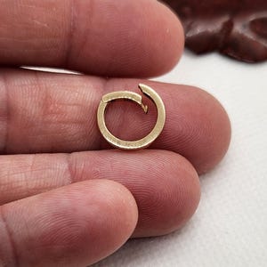 May include: A gold-colored metal ring with a unique design. The ring is open and has a small gap on one side.