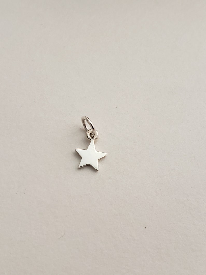 May include: A silver star charm with a loop for attaching to a necklace or bracelet.