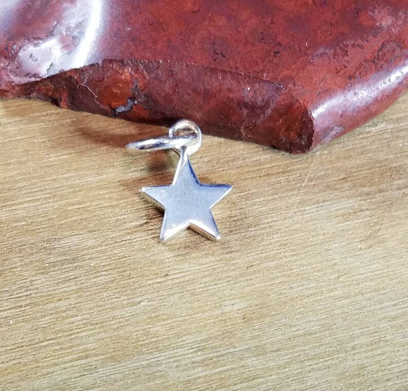 May include: A silver star charm with a loop for attaching to a necklace or bracelet.