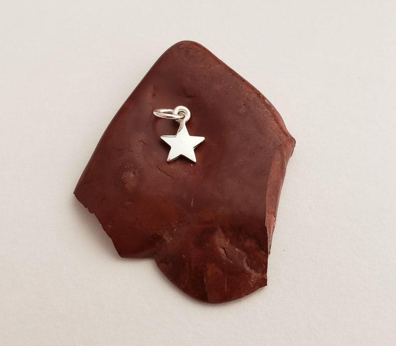 May include: A silver star charm pendant with a loop for attaching to a necklace or bracelet.