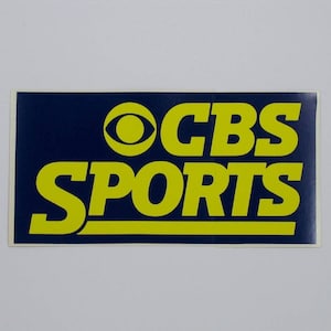 May include: A blue and yellow sticker with the CBS Sports logo. The logo features the CBS eye and the words "CBS SPORTS" in yellow.