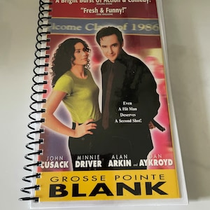 May include: A movie poster for the film Grosse Pointe Blank, featuring John Cusack, Minnie Driver, Alan Arkin, and Dan Aykroyd. The poster has a yellow background with black text and a photo of the actors.