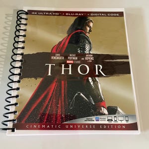 Puede incluir: Un disco Blu-ray 4K Ultra HD de la película Thor, con Chris Hemsworth, Natalie Portman y Anthony Hopkins. La portada muestra a Thor con una capa roja y sosteniendo su martillo. El texto "Thor" está en letras grandes y en negrita. El texto "Cinematic Universe Edition" está en la parte inferior de la portada.