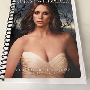 May include: A spiral-bound media case featuring Jennifer Love Hewitt on the cover for Ghost Whisperer The Fourth Season Discs 3 & 4. The cover art displays a portrait of the actor in a strapless cream-colored dress against a dark, moody forest background.