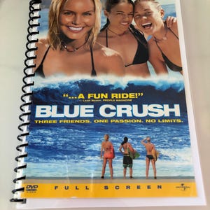 May include: A spiral-bound notebook featuring the Blue Crush movie poster on the cover. The cover displays three smiling individuals in bikinis, a large ocean wave, and the text: Collector's Edition, Blue Crush, Three Friends. One Passion. No Limits.