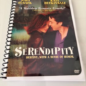 May include: A spiral-bound notebook featuring the Serendipity movie poster on the cover. The cover displays John Cusack and Kate Beckinsale, the title Serendipity, the tagline Destiny...with a sense of humor, and the quote A Matchless Romantic Comedy.