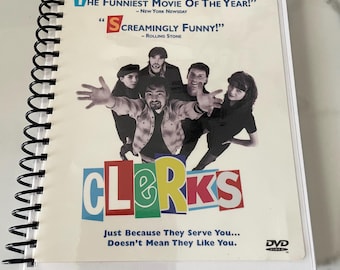 Könnte beinhalten: Eine DVD des Films "Clerks" in einem spiralgebundenen Gehäuse. Das Cover zeigt eine Gruppe von Personen und den Filmtitel in bunten Buchstaben. Der Text enthält Zitate von New York Newsday und Rolling Stone.