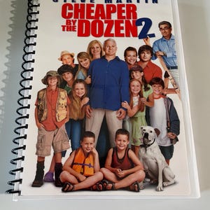 May include: A spiral-bound DVD case for the movie "Cheaper by the Dozen 2" featuring Steve Martin. The cover art shows a group of people, including children and a dog, with the movie title in red and white.