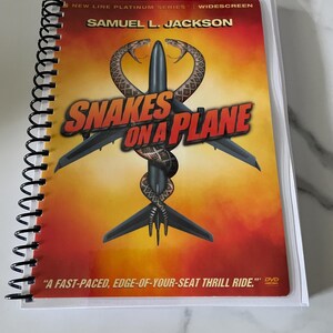 May include: A DVD of the movie "Snakes on a Plane" featuring Samuel L. Jackson. The cover art shows a snake wrapped around an airplane with a red and orange background. The DVD is in a clear plastic case.
