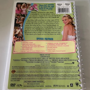 May include: DVD case for the movie "A Cinderella Story" starring Hilary Duff. The case is pink and green with a picture of Hilary Duff on the front. The back of the case lists special features, including additional scenes, music videos, and a behind-the-scenes look at the making of the movie.