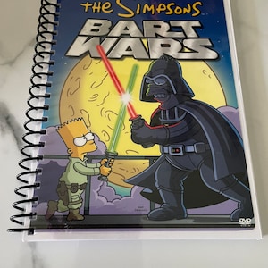 Puede incluir: Una carátula de DVD para "Los Simpson: La Guerra de los Bart" con Bart Simpson como Luke Skywalker y Homer Simpson como Darth Vader. La carátula es blanca con un fondo azul y presenta una luna amarilla.