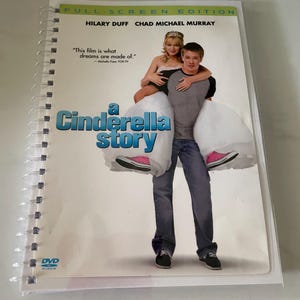 May include: DVD cover for the movie "A Cinderella Story" starring Hilary Duff and Chad Michael Murray. The cover features a photo of the two actors, with Duff wearing a white dress and Murray carrying her on his back. The text "This film is what dreams are made of." is printed on the cover.