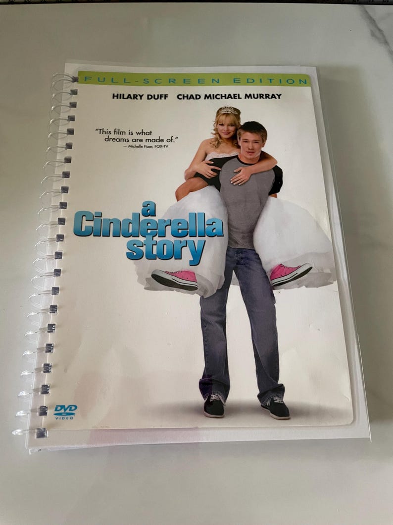 May include: DVD cover for the movie "A Cinderella Story" starring Hilary Duff and Chad Michael Murray. The cover features a photo of the two actors, with Duff wearing a white dress and Murray carrying her on his back. The text "This film is what dreams are made of." is printed on the cover.