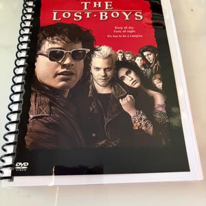 May include: A spiral-bound booklet featuring the cover art for The Lost Boys Two-Disc Special Edition DVD. The cover displays the film title, the tagline Sleep all day. Party all night. It's fun to be a vampire., and a cast photo on a red background.