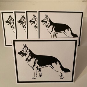 May include: Greeting cards featuring a black and white illustration of a German Shepherd dog. The cards have a white background with a black border. The dog is depicted in profile, with its tongue out.