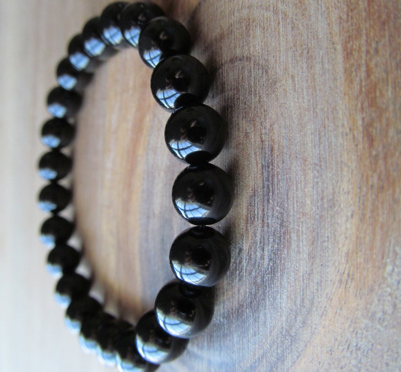 May include: A black beaded bracelet with round, shiny beads.