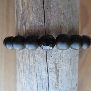 Op de afbeelding: Zwarte onyx kralen armband met een gefacetteerde onyx kraal in het midden.
