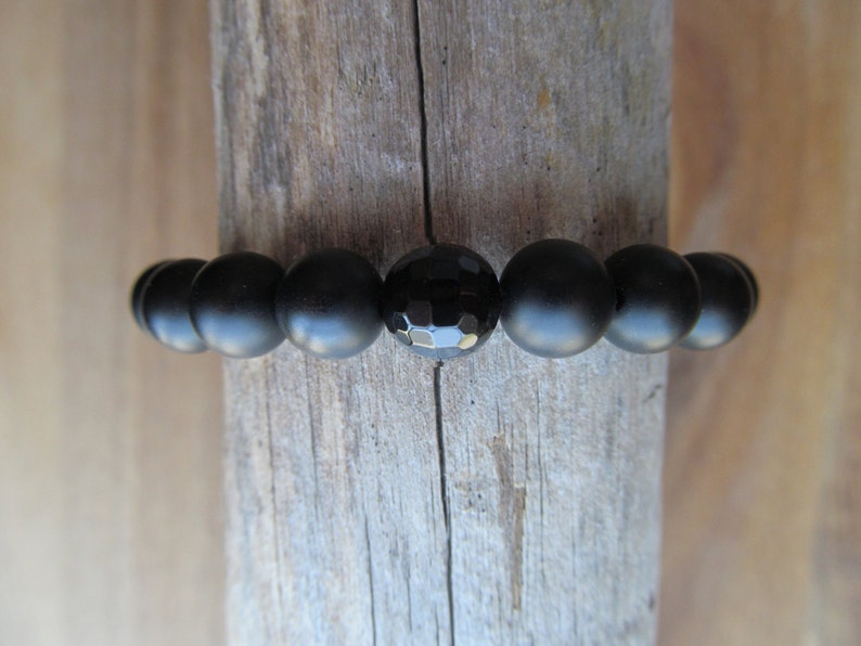 Op de afbeelding: Zwarte onyx kralen armband met een gefacetteerde onyx kraal in het midden.