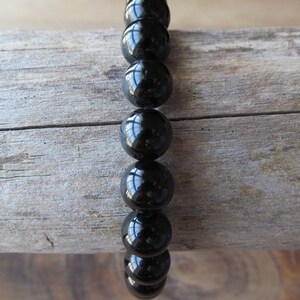May include: A black beaded bracelet with shiny, round beads.