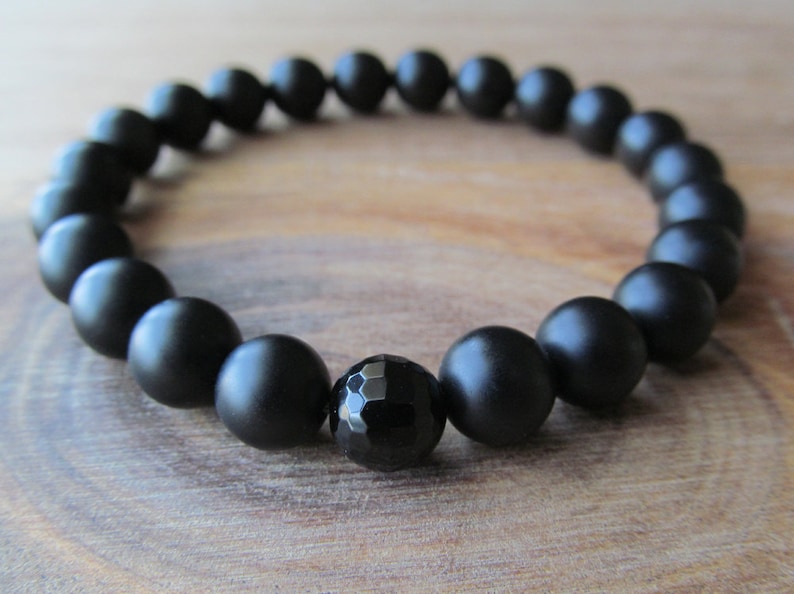 Op de afbeelding: Een zwarte onyx armband met matte zwarte kralen en een gefacetteerde zwarte onyx middelste kraal.