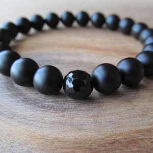 Op de afbeelding: Een zwarte onyx armband met matte kralen en een gefacetteerde zwarte onyx middelste kraal.