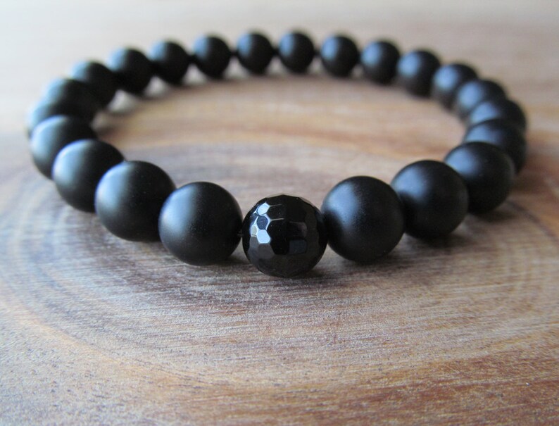 Op de afbeelding: Een zwarte onyx armband met matte kralen en een gefacetteerde zwarte onyx middelste kraal.