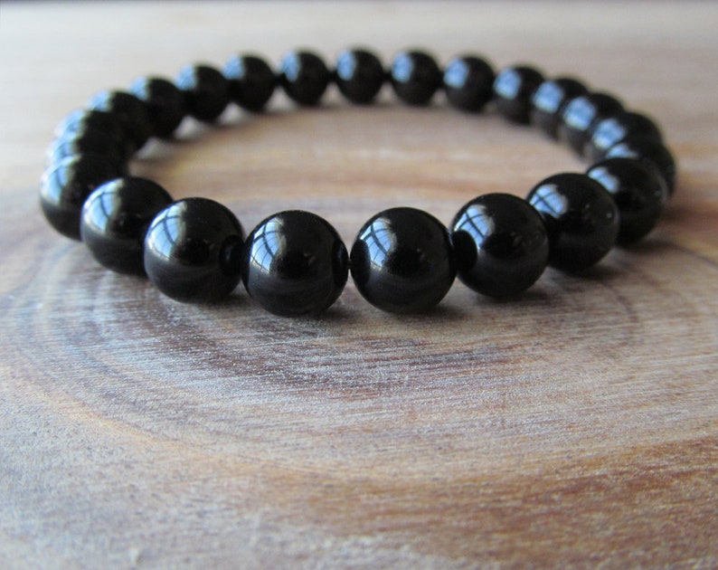 May include: A black beaded bracelet with round, shiny beads.