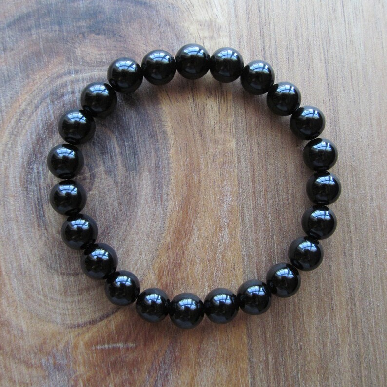 May include: A black beaded bracelet with round, polished beads. The bracelet is made of natural black onyx stones.