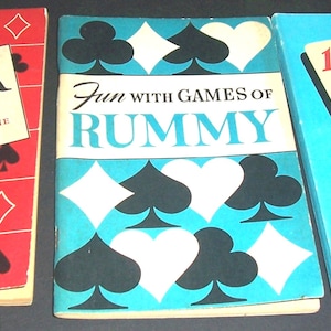 May include: Three vintage card game books: "Poker," "Fun with Games of Rummy," and "150 Ways to Play Solitaire." The "Poker" book is red with card suit symbols. The "Rummy" book is turquoise with black and white card suit symbols. The "Solitaire" book is light blue.