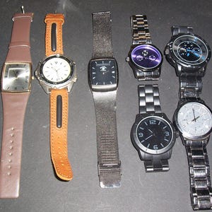 Pode incluir: Uma cole&ccedil;&atilde;o de seis rel&oacute;gios de pulso com designs variados. Est&atilde;o inclu&iacute;dos dois rel&oacute;gios com pulseiras de couro em castanho e bege, um com bracelete de malha escura e tr&ecirc;s rel&oacute;gios de elos met&aacute;licos em prateado, preto e cinzento escuro.