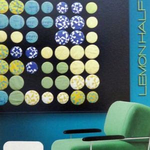 May include: A green armchair with white straps and black armrests sits in front of a wall with a blue background. The wall has a pattern of colorful circles with different designs. The text "ZEN CHIC" is visible on a white sign in the lower left corner of the image. The text "LEMON HALETONE" is visible on a blue background in the upper right corner of the image.