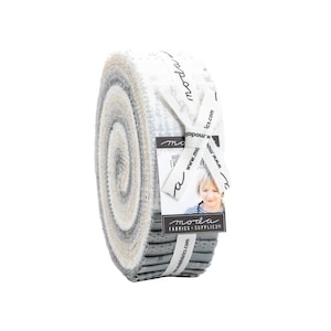 May include: A roll of fabric with a white background and gray and beige stripes. The fabric is rolled up and tied with a white ribbon. The ribbon has a black label with the text "moda fabrics + supplies" and a website address. The fabric is a Moda fabric.