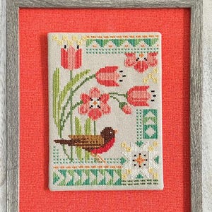 May include: A cross stitch pattern featuring a robin bird and spring flowers in a framed design. The pattern is titled "Seasonal Courier: Robin's Spring" and is by Robin Pickens Cross Stitch Patterns.
