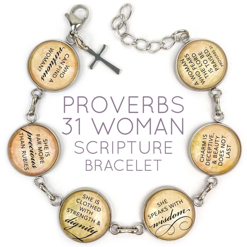 May include: A silver bracelet with charms featuring quotes from Proverbs 31. The charms are round and have a vintage, parchment-like background. The text on the charms includes "She is far more precious than rubies", "She is clothed with strength & dignity", "She speaks with wisdom", "A woman who fears the Lord is to be praised", and "Charm is deceptive, & beauty does not last".