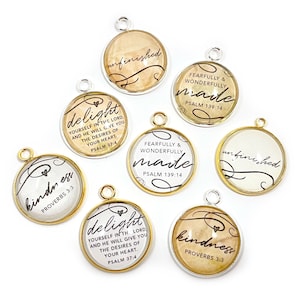 May include: Assortment of eight round glass charms with gold and silver trim. Each charm features a different inspirational quote and scripture reference. The quotes include "delight yourself in the Lord", "fearfully and wonderfully made", "kindness", and "unfinished".