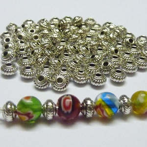 May include: A selection of silver metal beads and a beaded strand. The strand includes colourful glass beads in green, red, yellow, and blue, separated by silver beads. Suitable for jewellery making.
