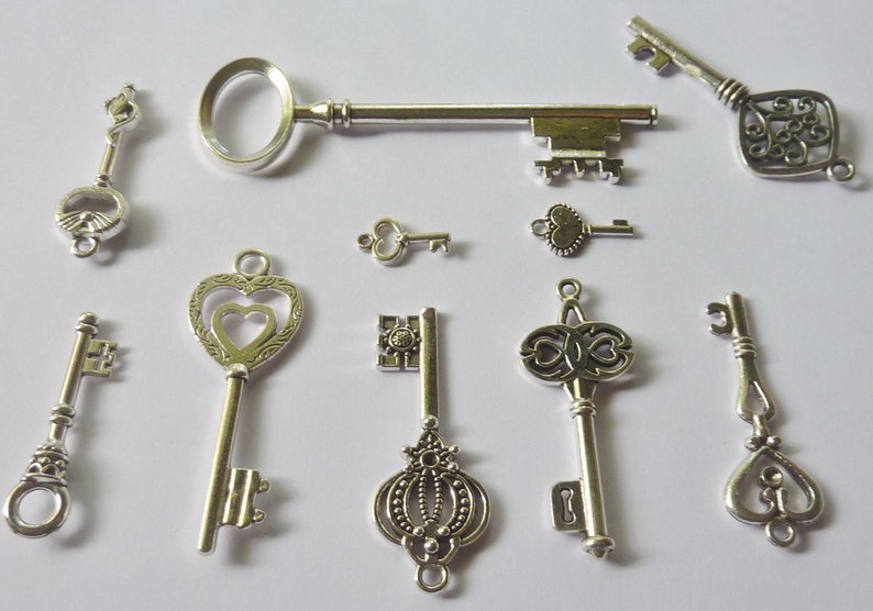 May include: A collection of ten silver-toned skeleton keys with various ornate designs. The keys are arranged on a white background.