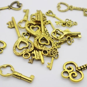 May include: A pile of antique gold-toned skeleton keys with ornate heart-shaped keyholes. The keys are scattered on a white surface.