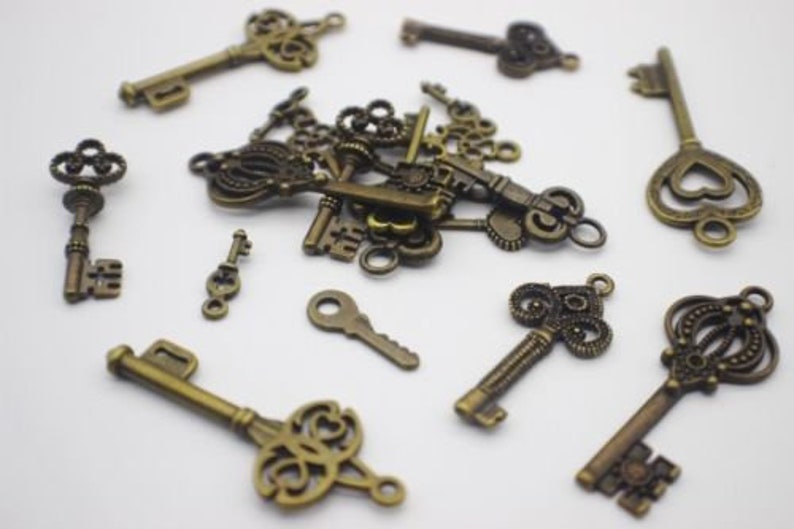 May include: A collection of antique-style keys in a bronze finish. The keys are various sizes and shapes, with intricate details and ornate designs. Some keys have heart-shaped keyholes.