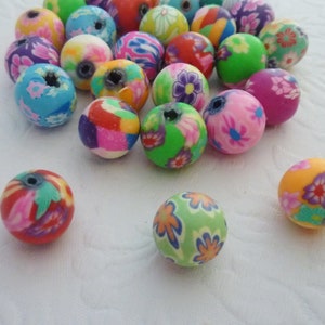 May include: A collection of colourful round beads with floral patterns. The beads are made of polymer clay and are approximately 1 inch in diameter.