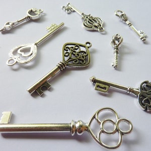 May include: A collection of ten silver-toned skeleton keys with intricate designs. The keys are arranged on a white surface.