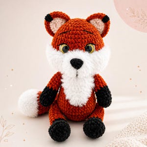 May include: A crocheted fox toy in shades of orange, white, and black. The fox has a fluffy white chest and face, with black paws and tail tip. The eyes are yellow. The toy is handmade.